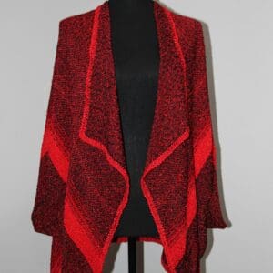 Red and black knitted shawl on mannequin.